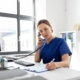 Image of a medical professional writing on a clipboard while on a phone call.