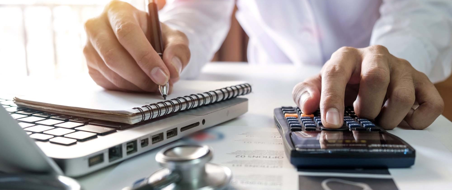 Healthcare costs and fees concept.Hand of smart doctor used a calculator and smartphone for medical costs at modern hospital in sun light