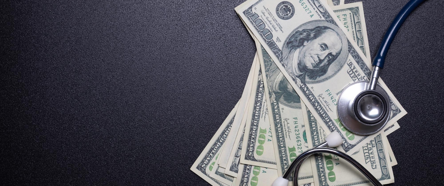 Top down view of several one hundred dollar bills with a stethoscope covering them Top down view of several one hundred dollar bills with a stethoscope covering them
