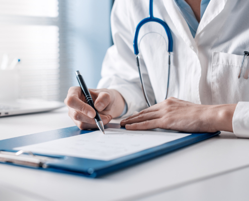 Side view of a doctor writing on a clipboard