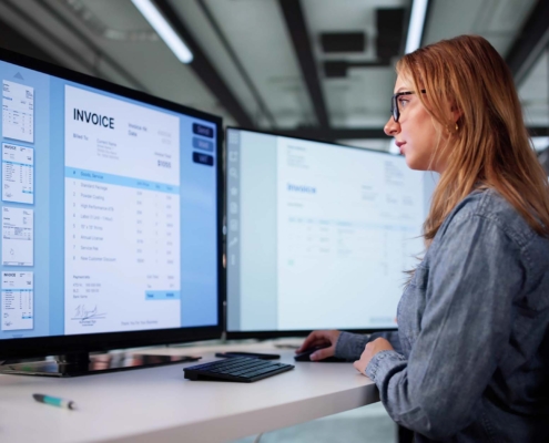 Worker looking at invoices on computer monitor